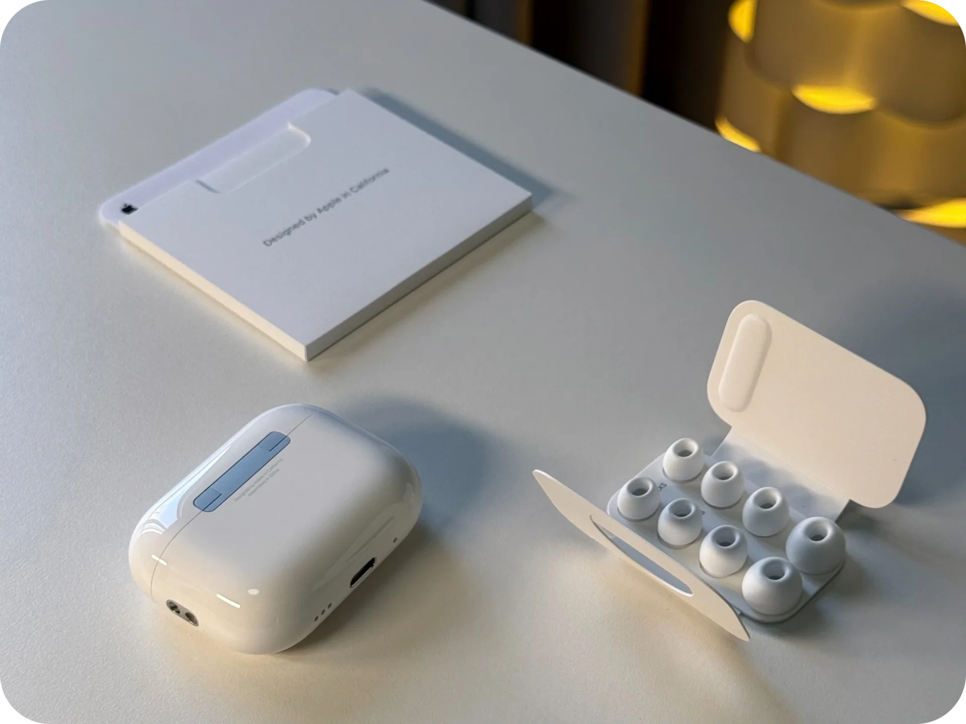 A white earbud charging case, interchangeable ear tips and packaging on a table